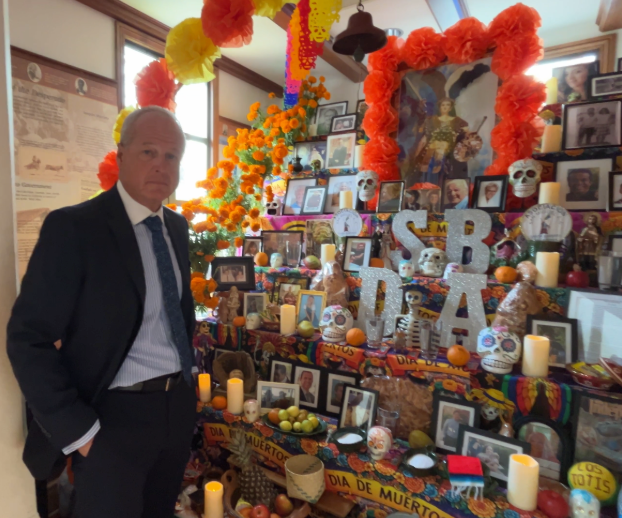 Santa Barbara County District Attorney John Savrnoch stands in front of ofrenda